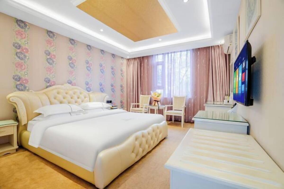 A hotel room with a large bed, bedside tables, a desk, and a chair.
