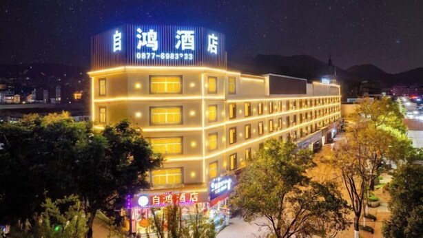 A hotel with a prominent illuminated sign, multiple floors, and a well-lit facade. - Zihong Hotel (Yuxi)