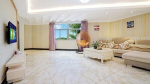 A modern living room with a sofa, a hanging chair, a coffee table, and a TV mounted on the wall. - Zihong Hotel (Yuxi)