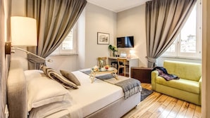 A hotel room with a bed, a desk, a TV, and a sofa. -  magenta collection navona (Rome)