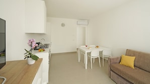 A modern, minimalistic living space with a kitchen, dining area, and a sofa. - Appartamenti Alle Mura (Lazise)
