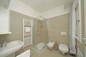 Enjoy a refreshing shower in the bathroom, featuring a glass-enclosed shower, handheld showerhead, and standalone bidet.