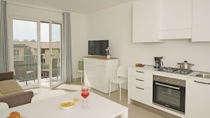 A modern kitchen with white cabinets, a built-in oven, and a dining area with a table and chairs. - Appartamenti Alle Mura (Lazise)