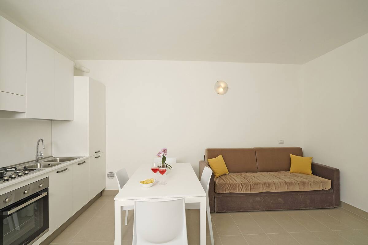 A compact living space with a kitchenette, a dining table, and a sofa.