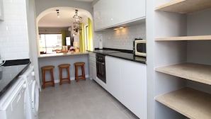Una cocina moderna con lavadora, taburetes de madera y microondas.