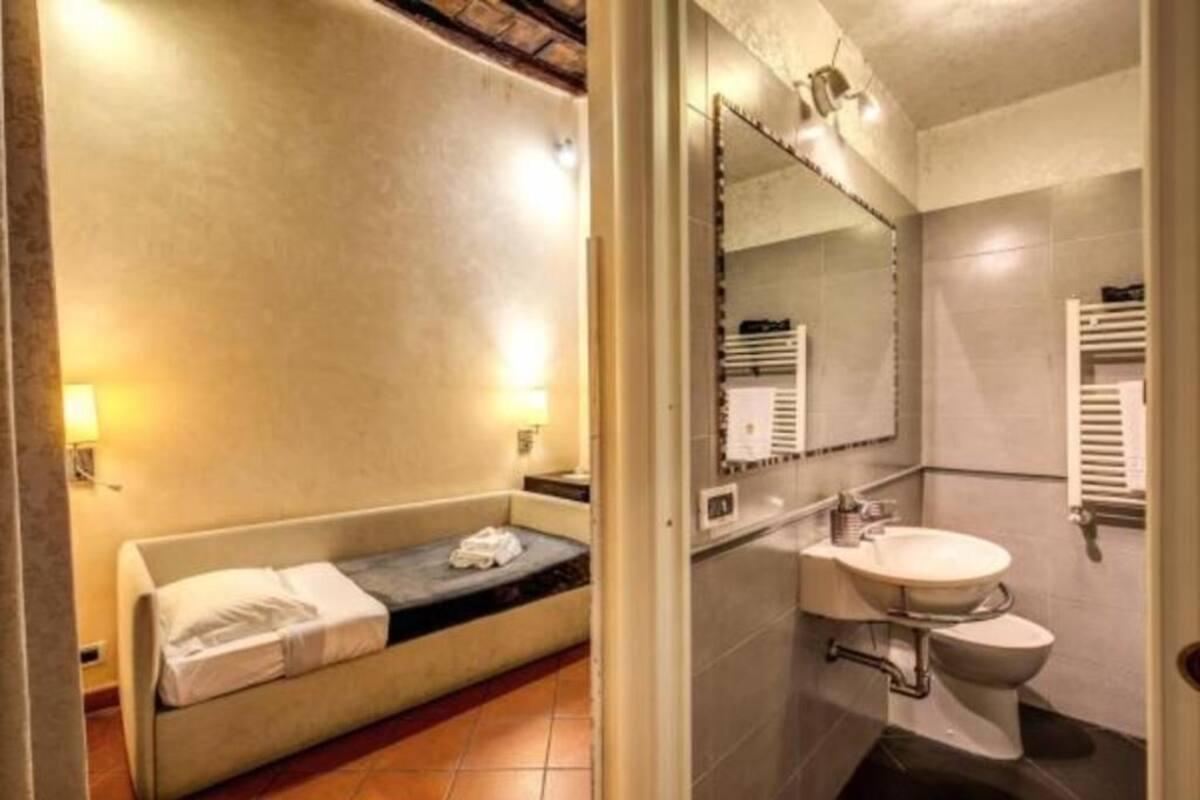 A compact room with a bed, a small sink, and a toilet.