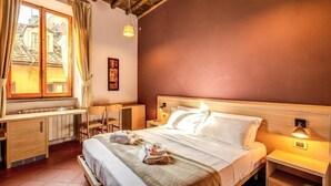 Ein Hotelzimmer mit Bett, Nachttischen, einem Schreibtisch und einem fenster mit Vorhängen.