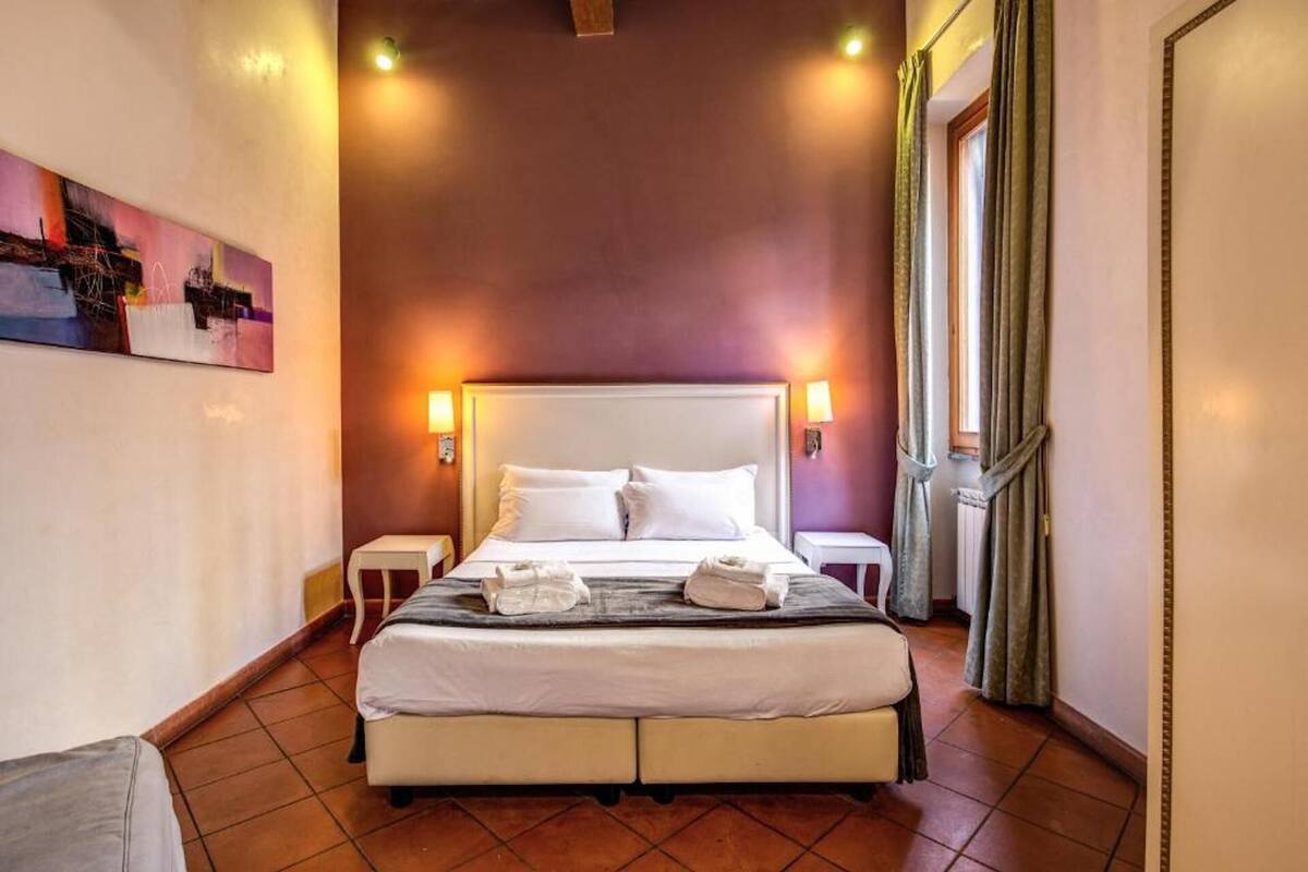 A hotel room with a large bed, two bedside tables, and a painting on the wall.