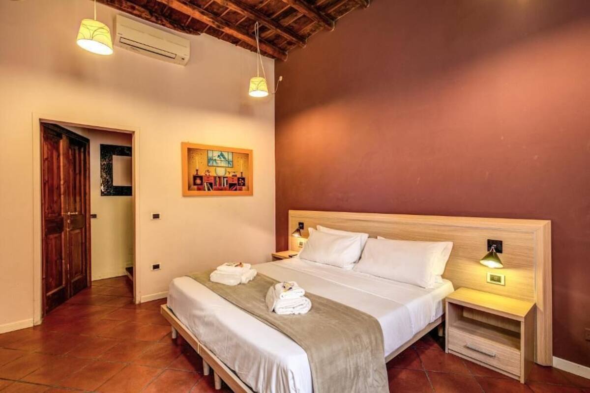 A bedroom with a wooden headboard, a bed with white linens, two bedside lamps, and a painting on the wall.