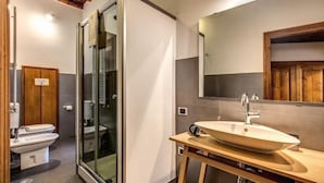 Ein modernes Badezimmer mit einer Duschkabine aus Glas, einem großen Waschbecken und einem Holz-Waschtisch.