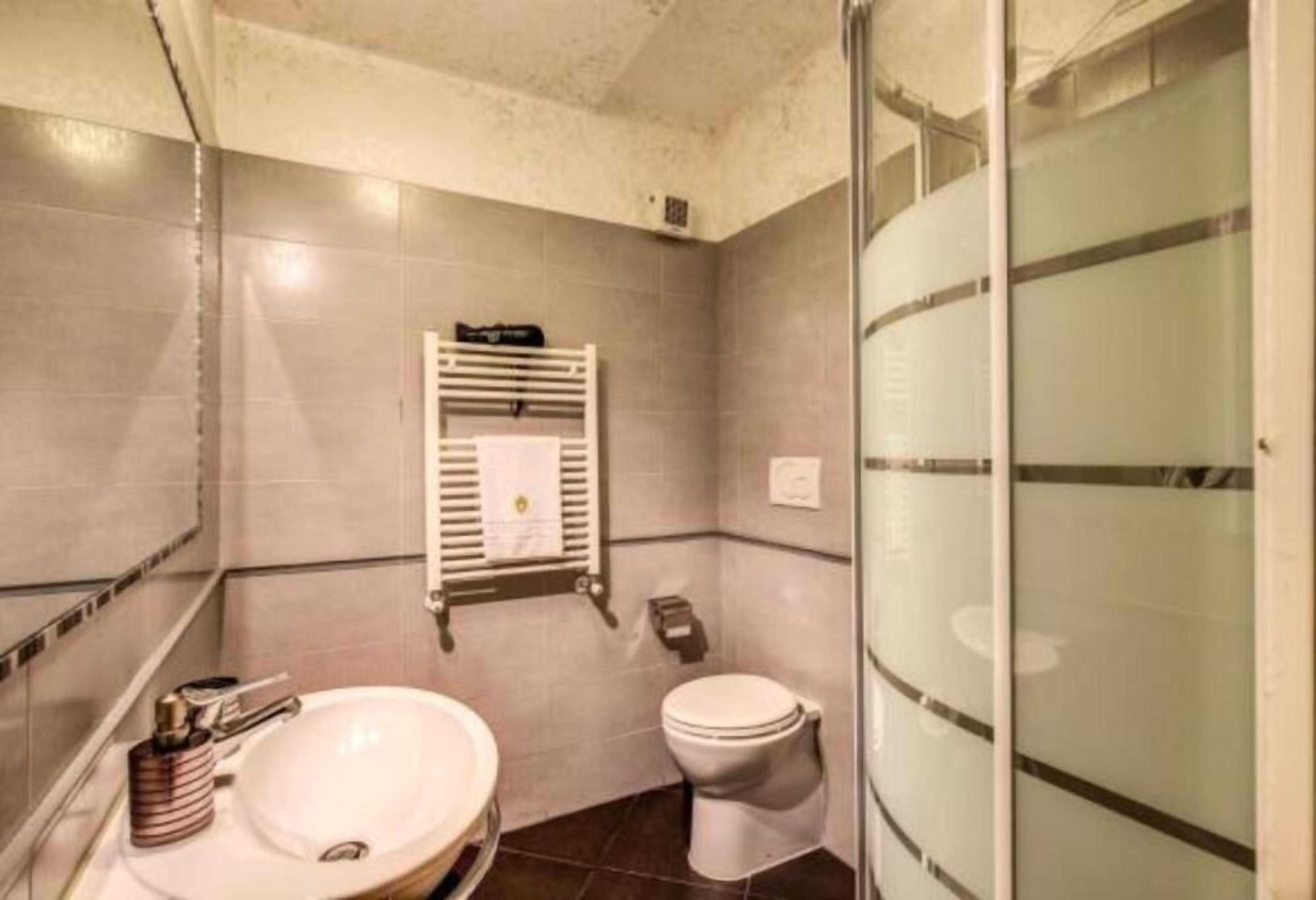 A bathroom with a sink, toilet, and a towel rack.