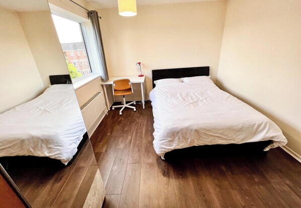 A hotel room with two single beds, a desk with a chair, a window, and a lamp. - Central Palace - Excellent Stay in London Zone 1 (London)