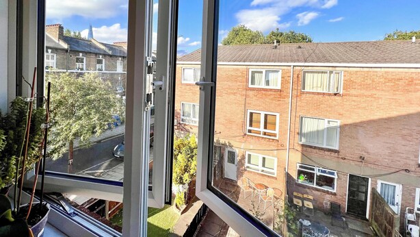 Une vue à travers la fenêtre d’un immeuble d’habitation doté de nombreuses fenêtres et d’une façade en briques.