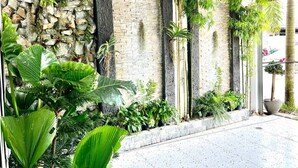 Façana moderna d'edifici amb pared de pedra i maó, jardí vertical i plantes grans en testos.