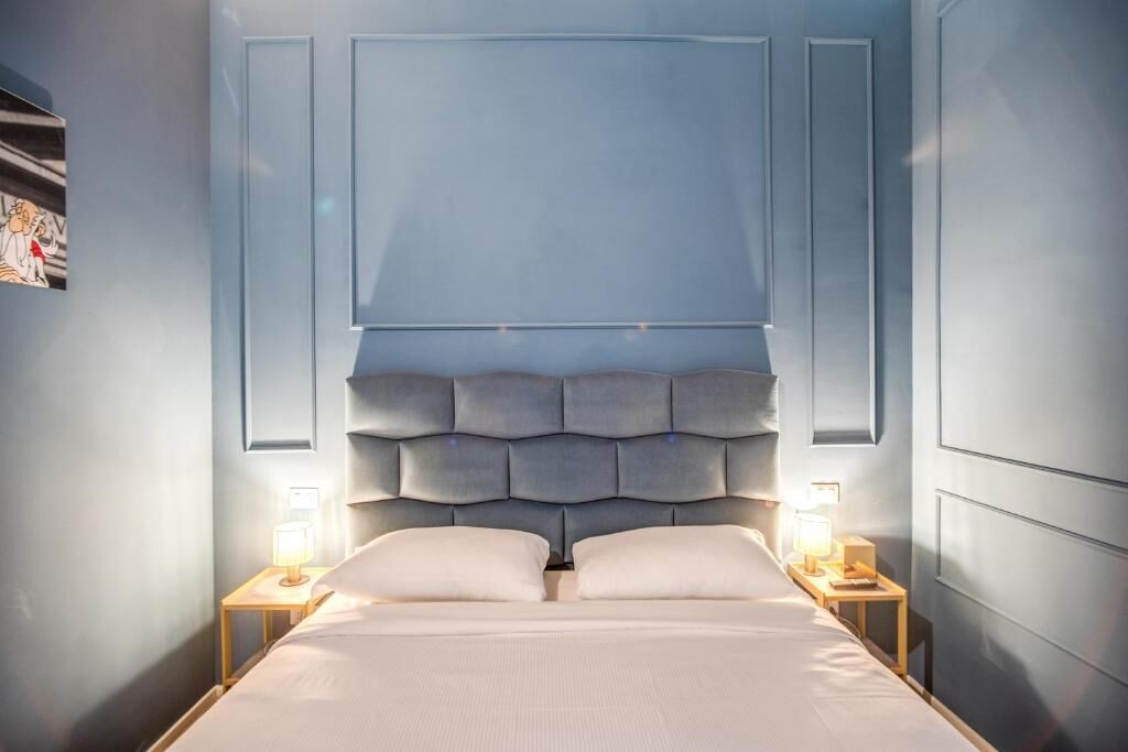 Een slaapkamer met een groot bed, twee nachtkastjes met lampen, en een hoofdbord met een geometrisch patroon.