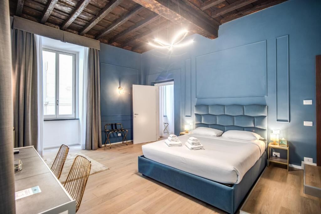 A modern bedroom with a large bed, a desk, and a chair.