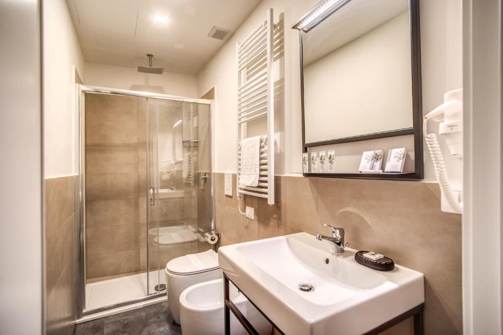 Un baño moderno con ducha envuelta en vidrio, un lavamanos blanco y un espejo sobre él.