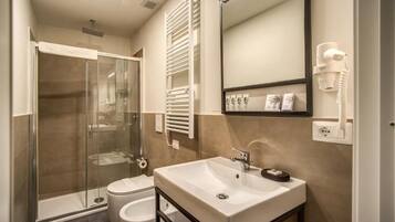 A modern bathroom with a glass shower enclosure, a white sink, a toilet, and a towel rack.