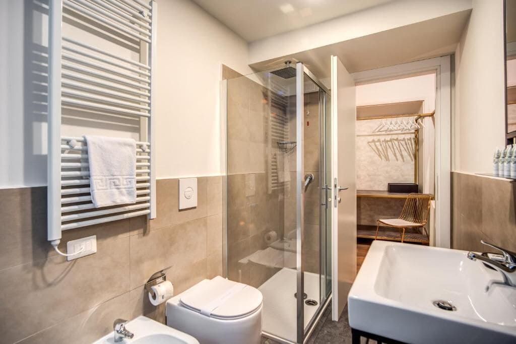 A modern bathroom with a glass shower enclosure, a white sink, and a toilet.