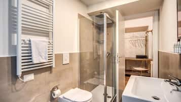 A modern bathroom with a glass shower enclosure, a white sink, and a toilet.