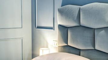 Een moderne slaapkamer met een gestuikt hoofdbord, een nachtkastje met een lamp, en een raam dat natuurlijk licht binnenlaat.