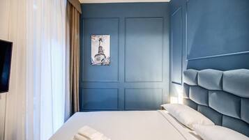 A hotel room with a large bed, a blue accent wall, and a framed picture of a building.