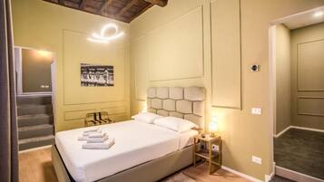 Una habitación de hotel con una cama, una mesita de noche, una lámpara de pared y una escalera.