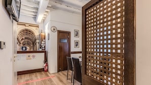 A hallway with wooden flooring, a fire extinguisher, and a wooden partition with a lattice design. - Magenta Collection Cancello (Rome)