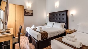 A hotel room with a large bed, a desk with a chair, a wardrobe, and a bedside table with a lamp. - Magenta Collection Cancello (Rome)