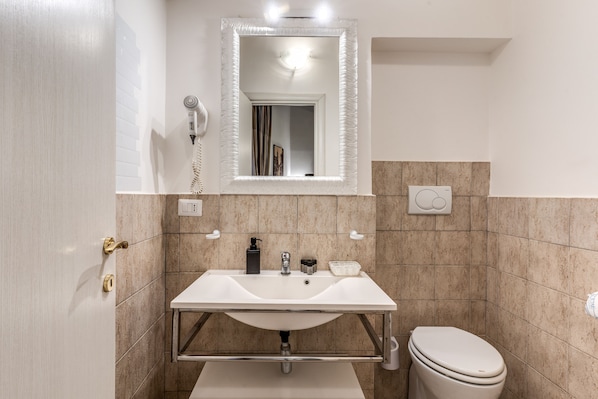 A bathroom with a white sink, a mirror, a hairdryer, and a toilet.