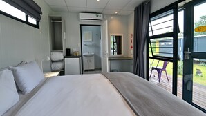 A hotel room with a bed, a desk, a small kitchenette, and a bathroom. - SleepOver Phabeni Gate (Mbombela)