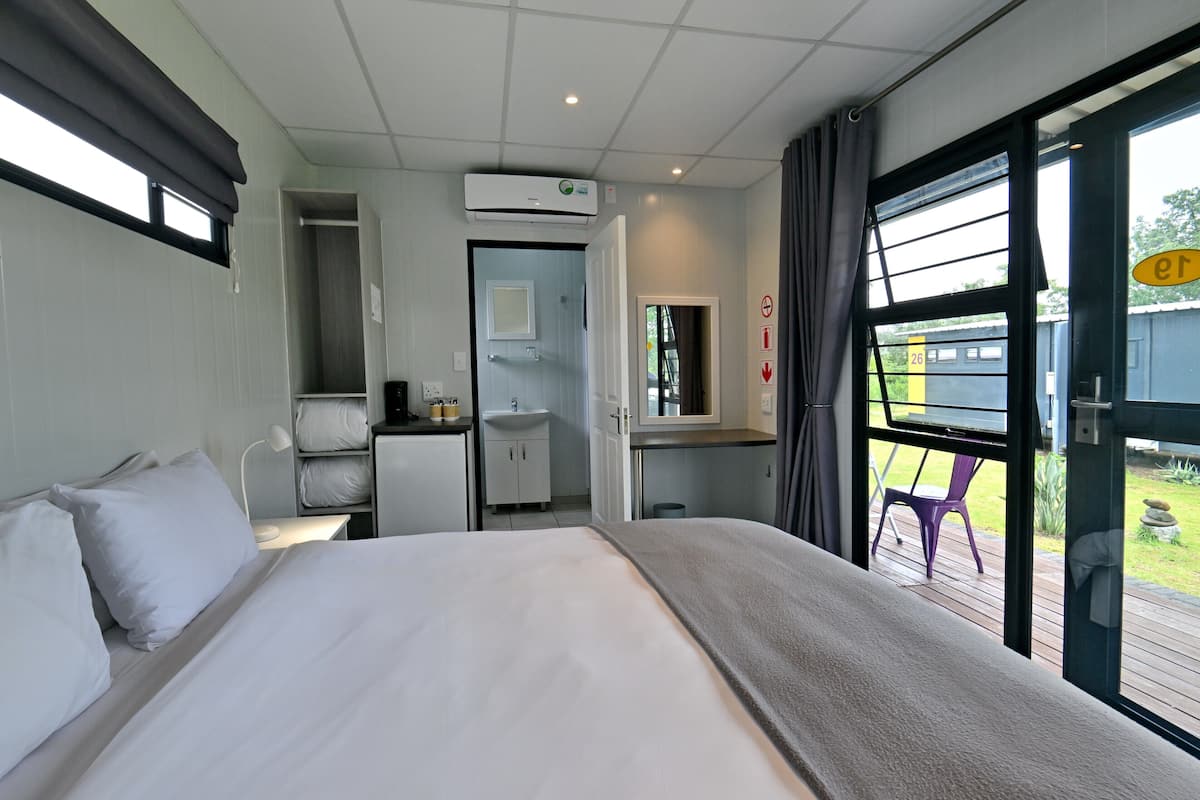 Ein Hotelzimmer mit Bett, Schreibtisch, einer kleinen Küchenzeile und einem Badezimmer.