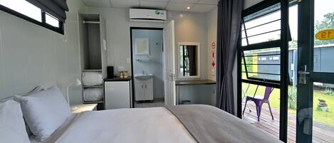 A hotel room with a bed, a desk, a small kitchenette, and a bathroom.