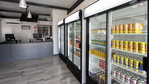 A modern, well-lit food court with refrigerated display cases stocked with various beverages and snacks. - SleepOver Phabeni Gate (Mbombela)