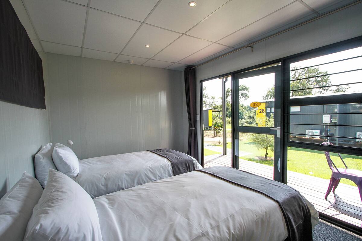 Ein modernes Hotelzimmer mit zwei Betten, einem großen Fenster und Blick nach außen.