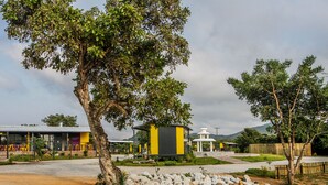 A building with a yellow and black facade, surrounded by a landscaped area with rocks and trees. - SleepOver Phabeni Gate (Mbombela)