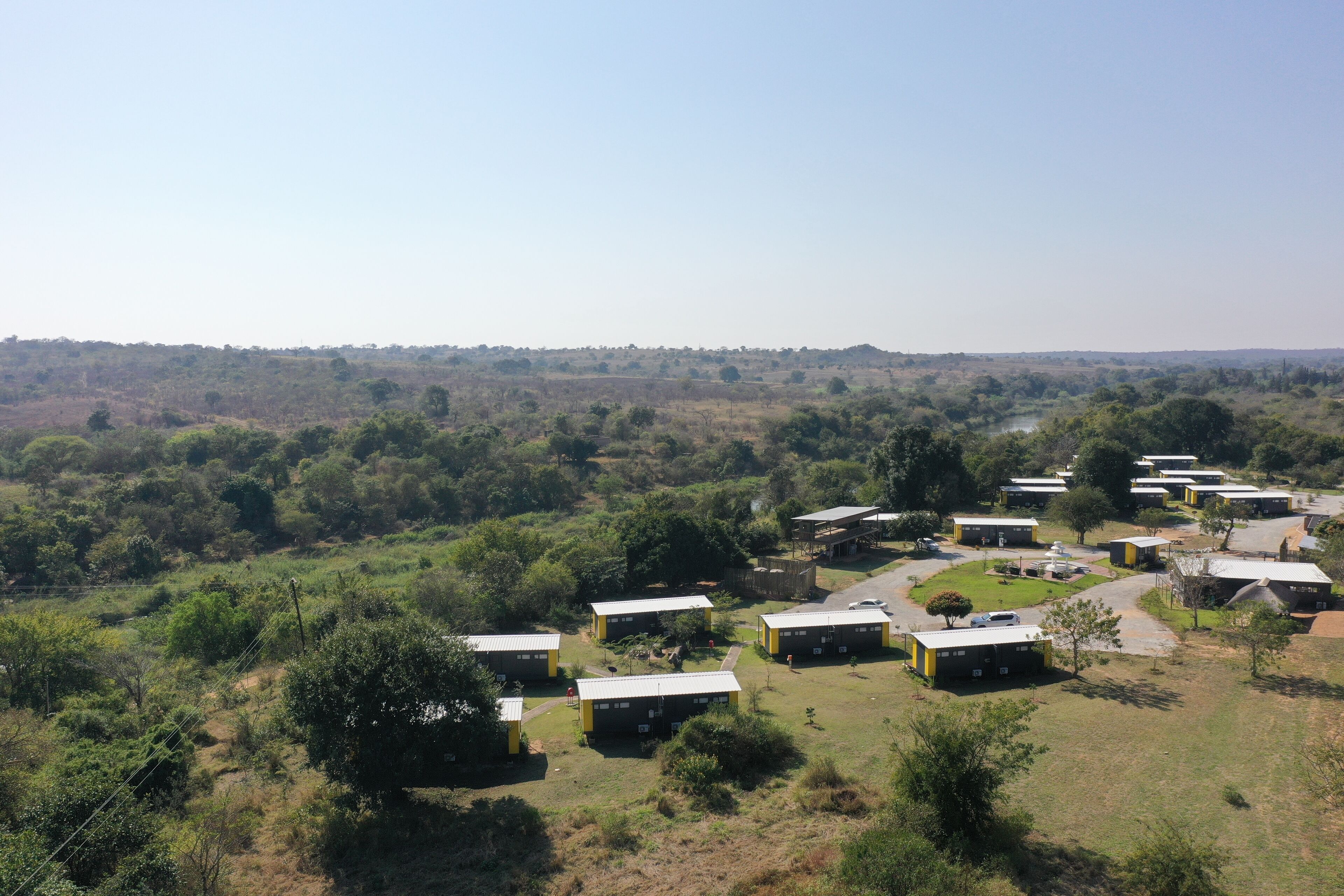 Un terrain de camping comprenant plusieurs cabanes jaunes et noires disposées en forme de demi-cercle.