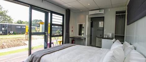 A hotel room with a bed, a desk, and a view of the outside.