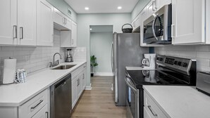 Una cocina moderna con armarios blancos, electrodomésticos de acero inoxidable y una isla central.