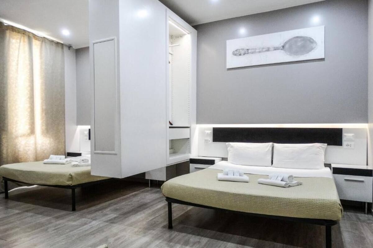 A modern hotel room with two beds, a large mirror, and a wall-mounted artwork.