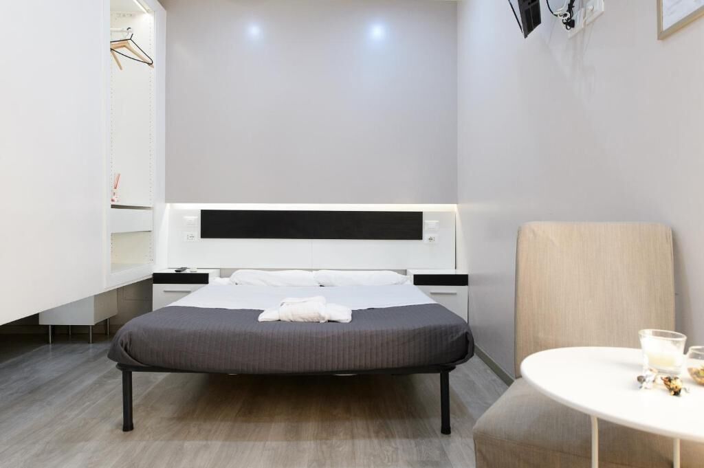 Une chambre d’hôtel moderne, équipée d’un lit, d’une table de chevet et d’une chaise.