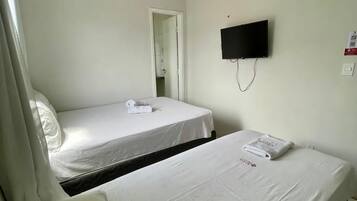 A hotel room with two beds, a flat-screen TV mounted on the wall, and a door leading to a bathroom.