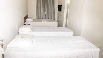 Een hotelkamer met twee enkele bedden, een aan de muur bevestigde televisie en een gordijn.