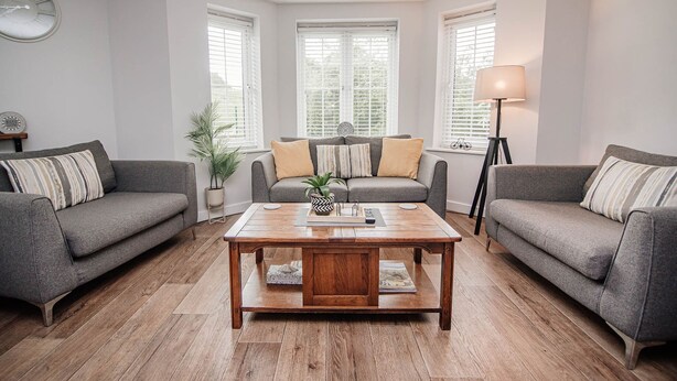 Un salon avec deux canapés gris, une table basse en bois et un lampadaire.