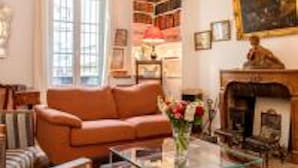 A living room with a sofa, a glass coffee table, and a fireplace. - Eiffel Tower Lourmel Residence  (Paris)