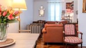 A living room with a sofa, armchair, and a table with a lamp and flowers. - Eiffel Tower Lourmel Residence  (Paris)