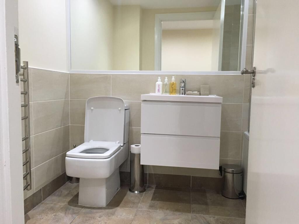 A modern bathroom with a toilet, a sink, and a mirror.