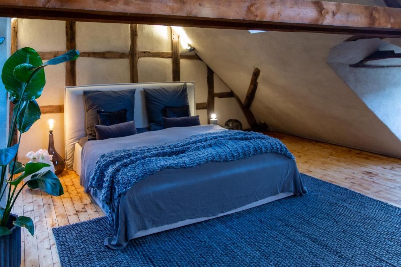 Un dormitorio acogedor con cama, almohadas, una colcha y suelo de madera.