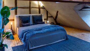 Un dormitorio acogedor con cama, almohadas, una colcha y suelo de madera.