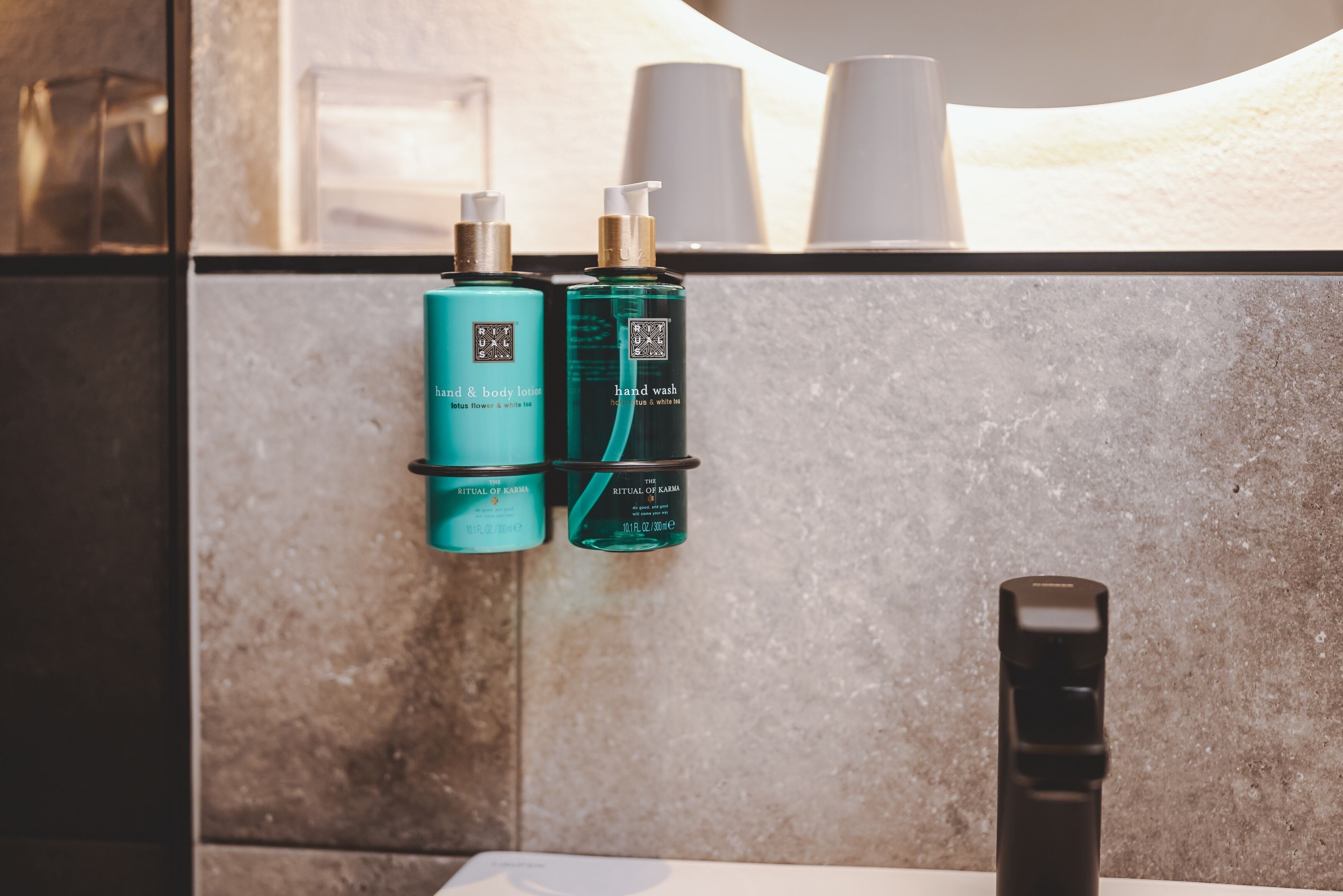 A bathroom with a mirror, two hand soap dispensers, and a black faucet.